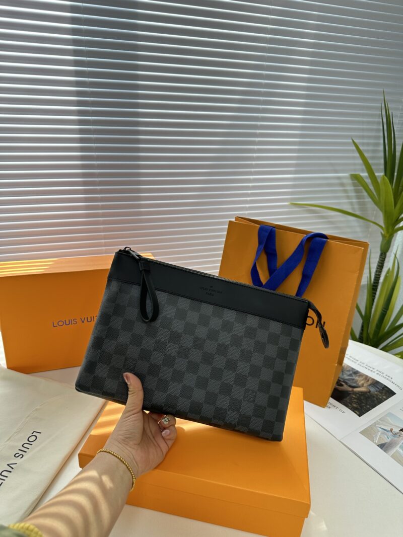 Exclusive real-life shot of M82543 Haige Pochette Voyage Souple handbag with packaging. Made of soft Monogram Eclipse coated canvas, the classic Pochette Voyage handbag lines are outlined with rounded strokes, providing a comfortable travel experienc...